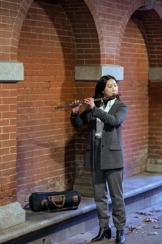 a young woman playing a flute on a city street