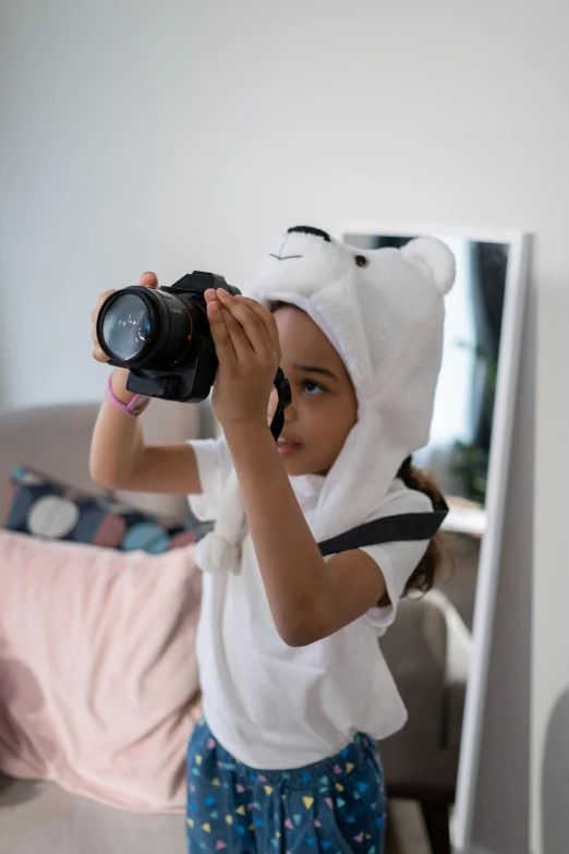 a girl is holding up her camera and wearing a bear hat