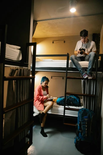 a boy on his phone sitting on top of bunk beds