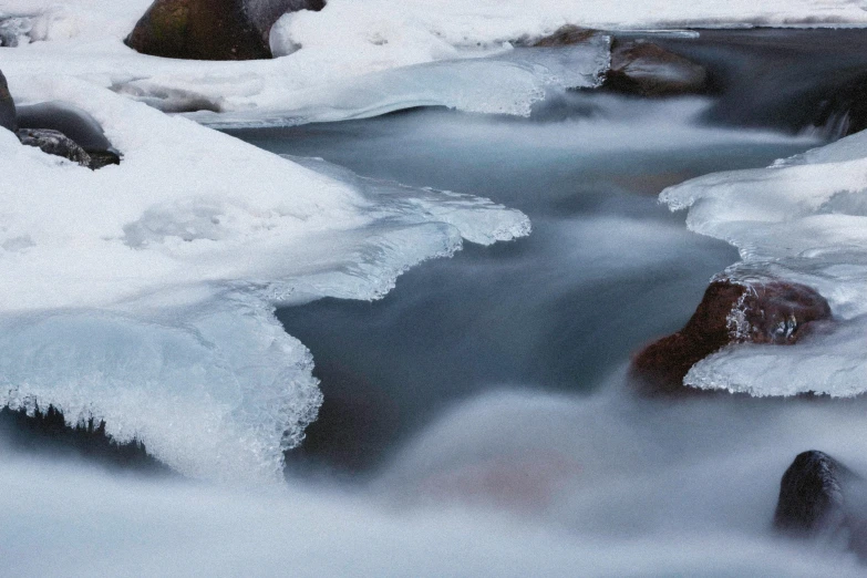 stream running through a rocky, frozen forest