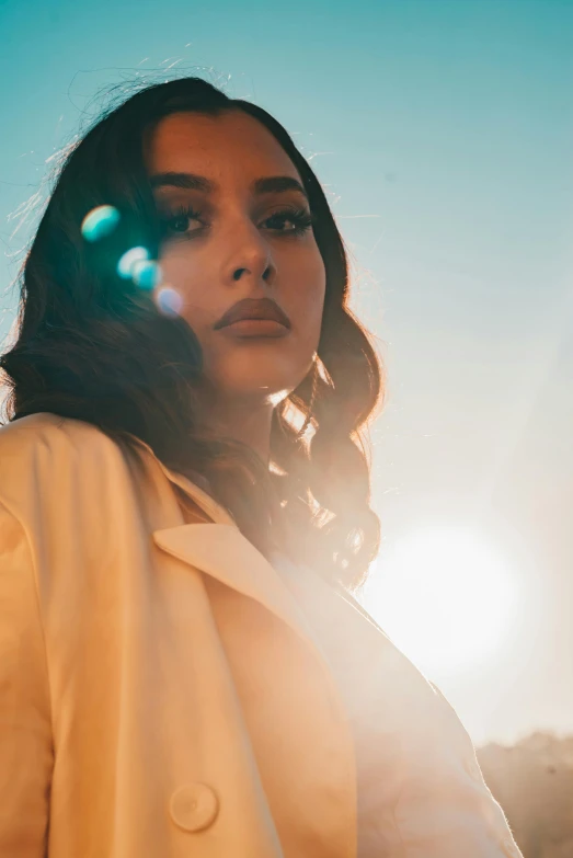 a woman posing in front of the sun wearing a white jacket