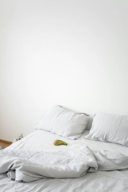 a white bed that has some sheets and pillows on top