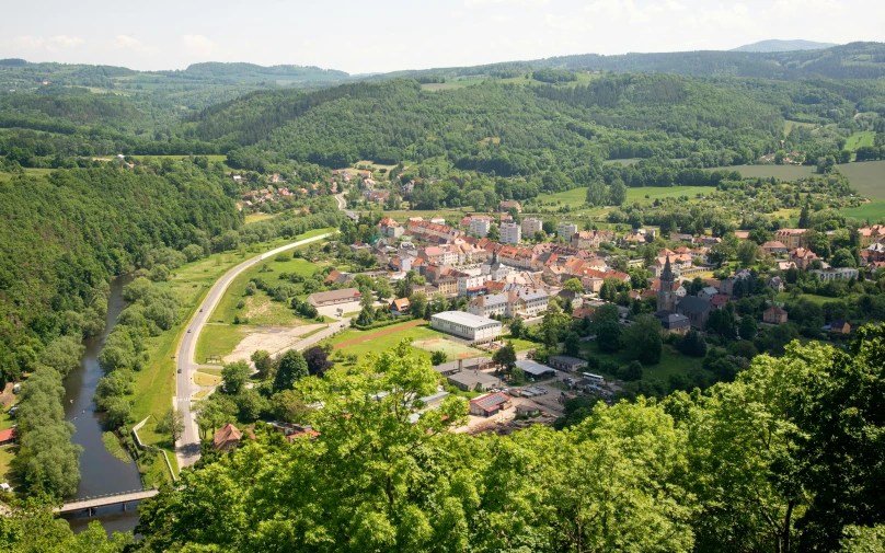 a small town nestled along a river in the middle of a green forest