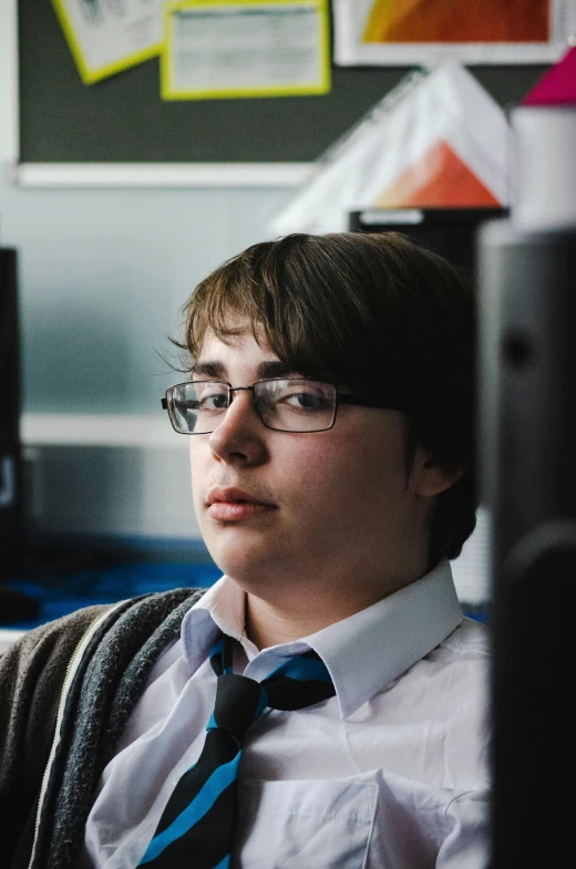 a person wearing glasses and a tie is sitting down