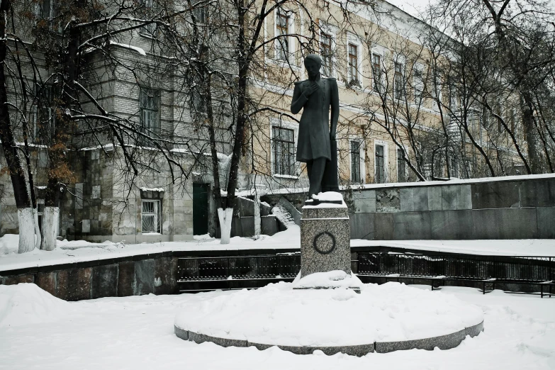 snow covering the ground, with a statue on a pedestal in front