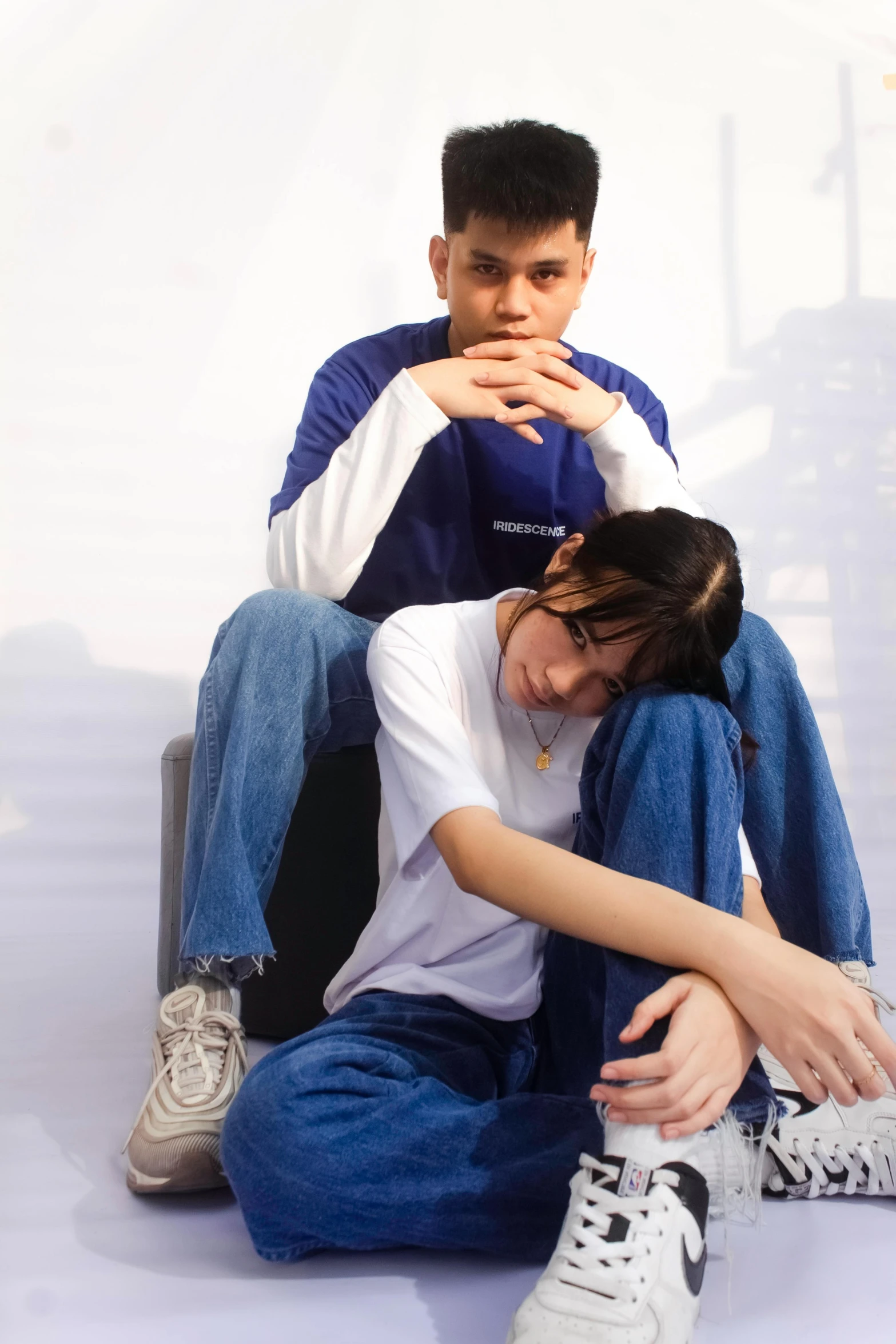 a woman sitting on the ground while her arm is around another mans lap