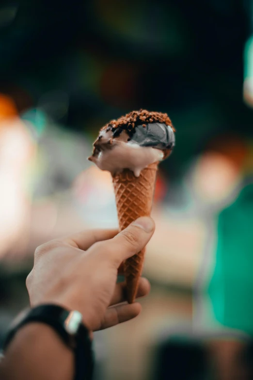 a person holding an ice cream cone in the middle of their hand
