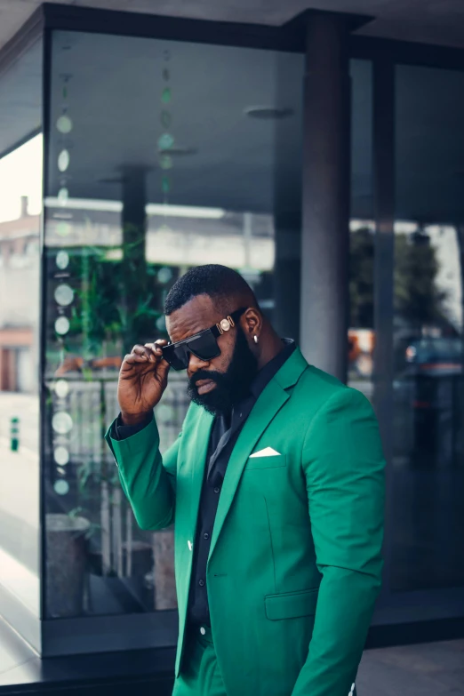 a man in a green suit holding a cell phone to his ear