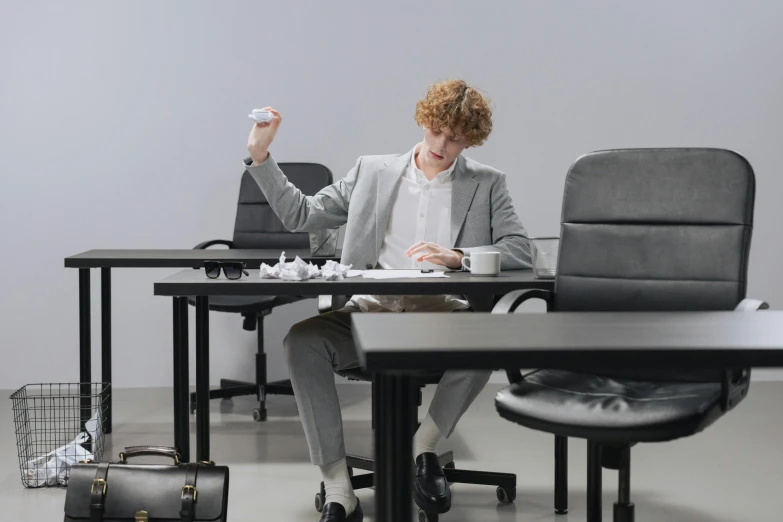 a woman sitting at a desk using a wii mote