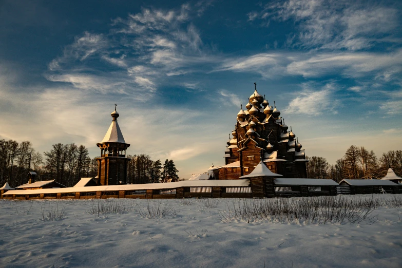 a snow covered field with a wooden church in the background