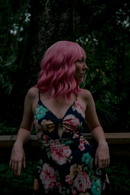 a woman with bright pink hair posing on a deck