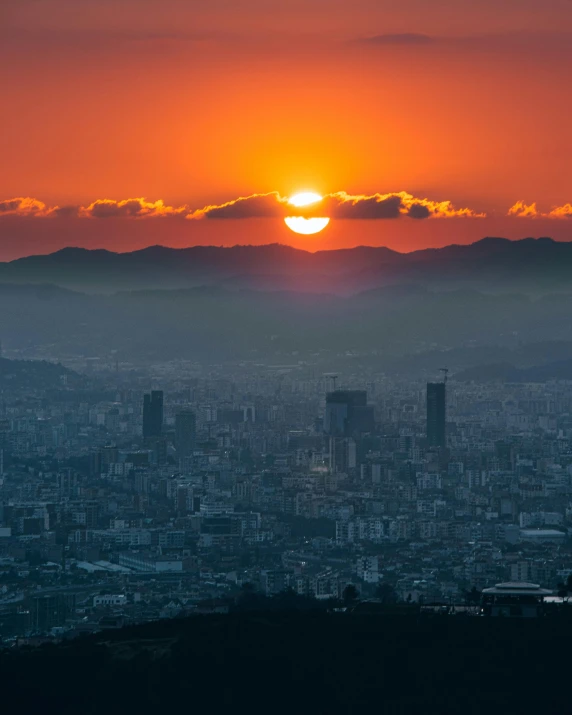 the sun setting behind an orange city skyline