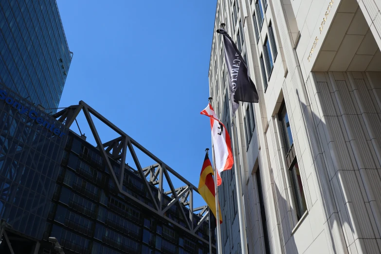 two flags flying from a flagpole on the side of a building