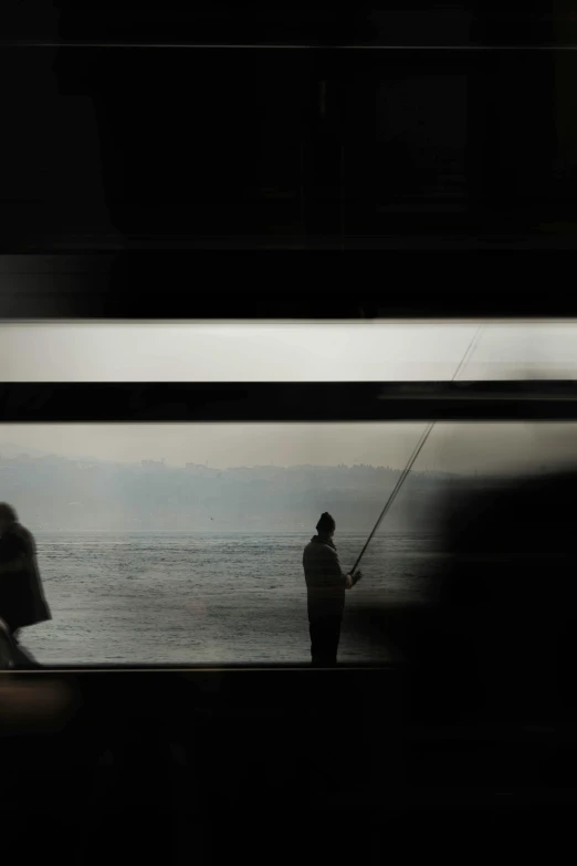 a silhouette of a person fishing near the beach