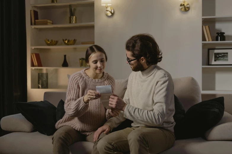 man and woman sitting on a couch looking at a tablet