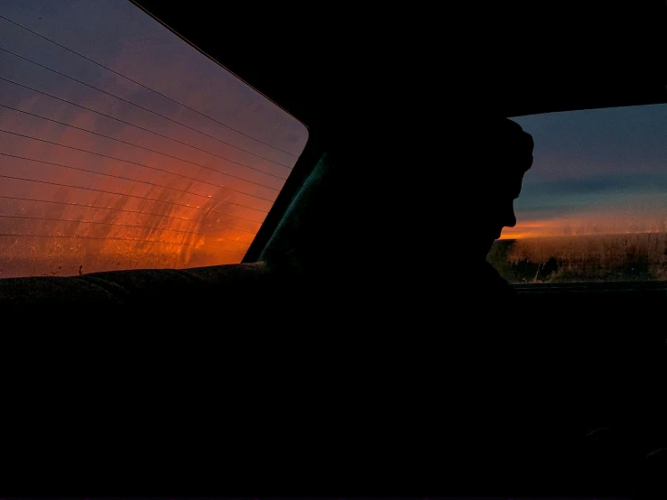 a view of a sun setting behind a car with the window partially covered