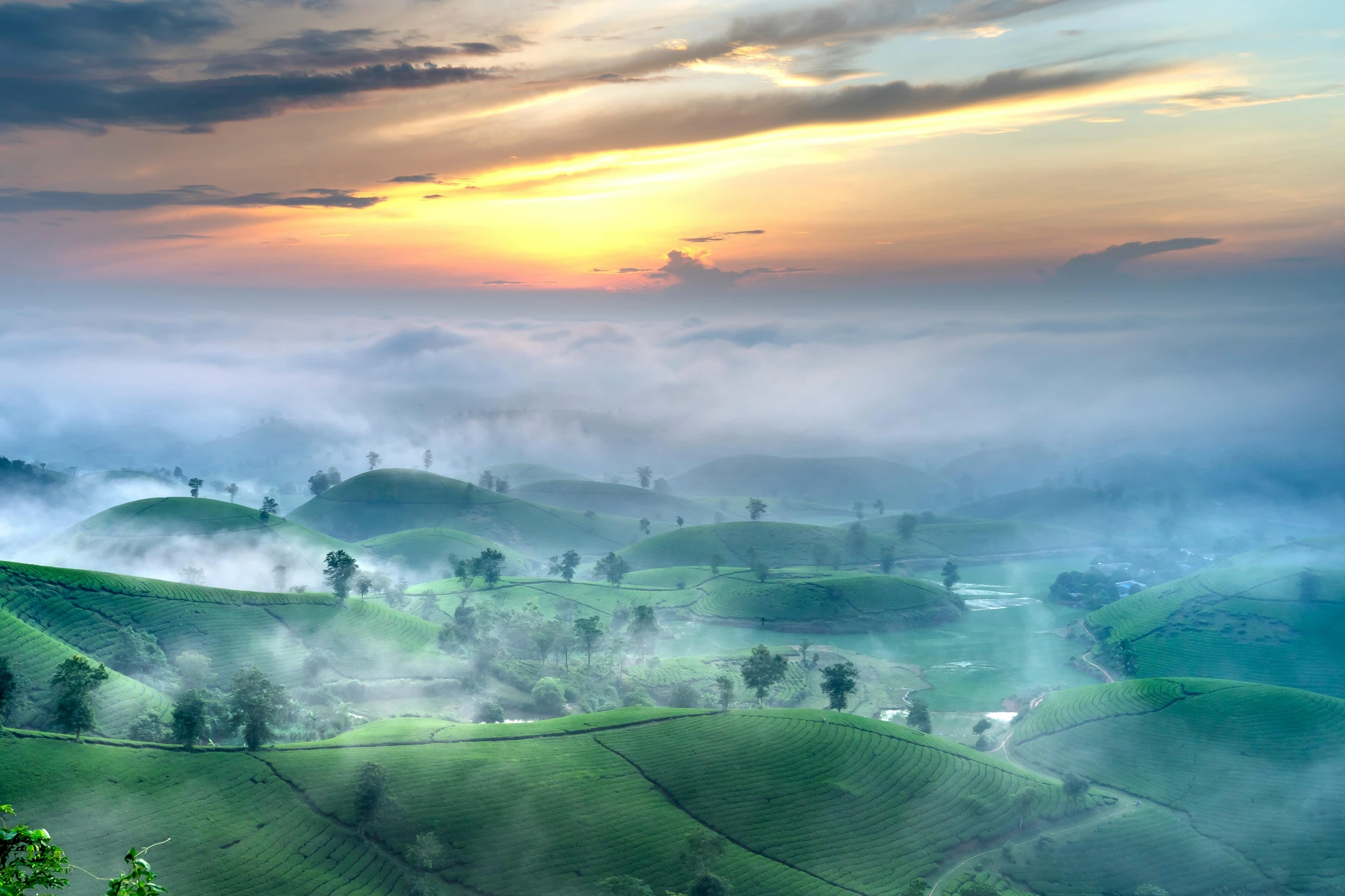 a valley filled with lush green hills under clouds