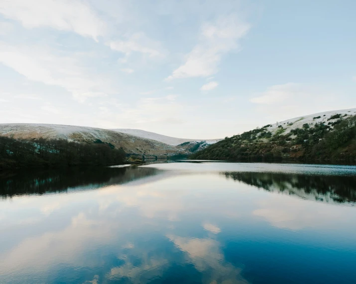 a body of water surrounded by mountains and clouds