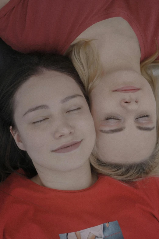 two people lying in bed with their faces together