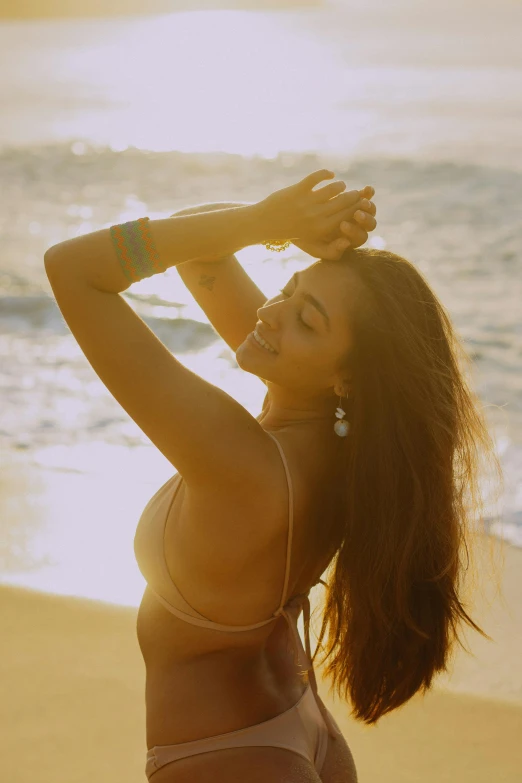 the back view of a woman in a bikini standing on a beach