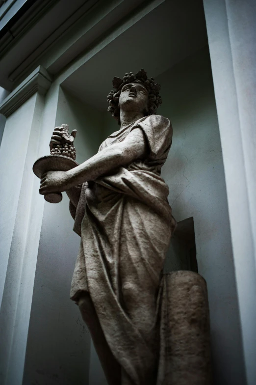 a statue holding a book and candle is in an open room