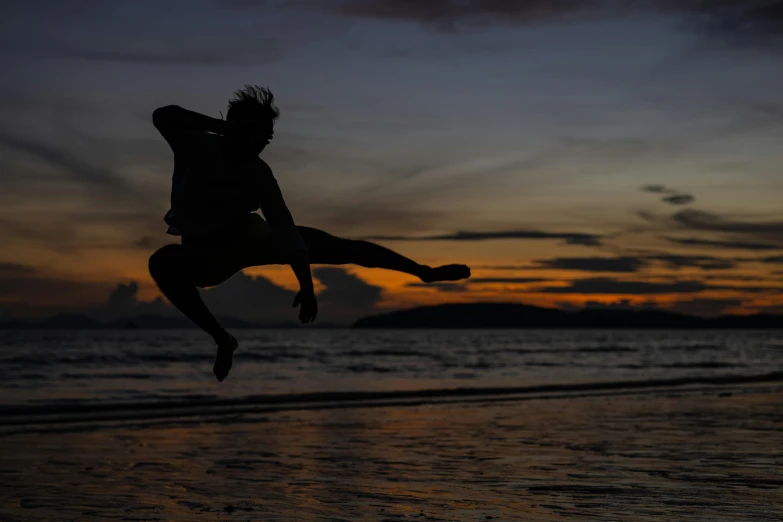 a man in shorts is silhouetted against the sunset on the beach