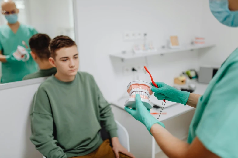 a man getting his teeth checked before he begins to trim another mans teeth