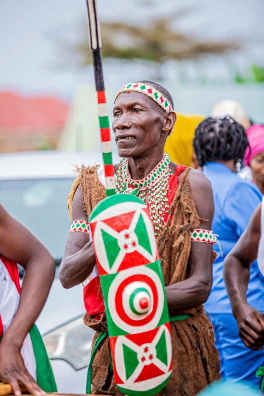 two men in african attire are holding onto a pole