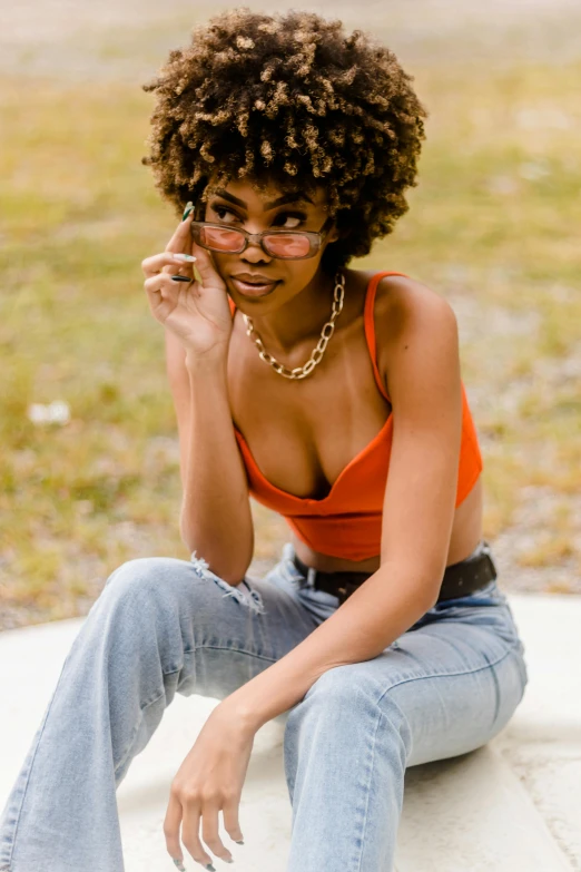 a black woman wearing jeans sitting down in the grass