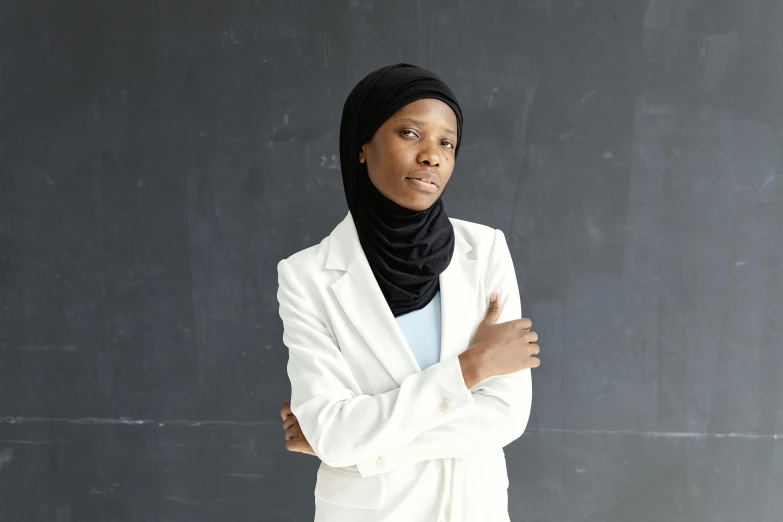 an african american woman in white jacket and scarf on a dark background