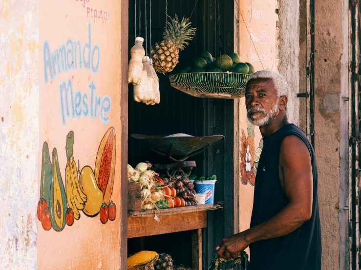 a man with beard standing in front of a fruit stand