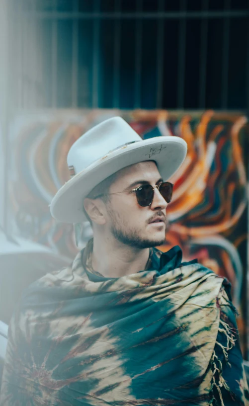 a man in a white hat, wearing sunglasses and a shawl