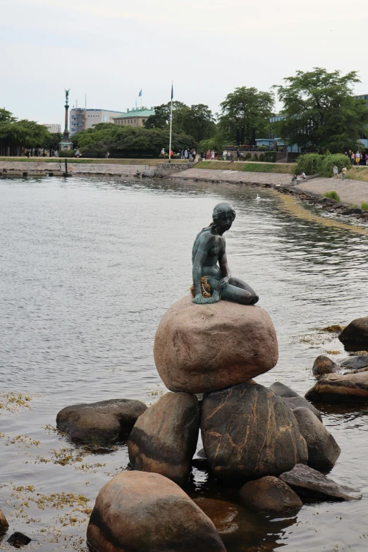 a little statue sitting on some rocks in the water