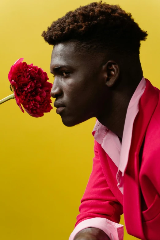 a young man wearing a red suit holding up flowers