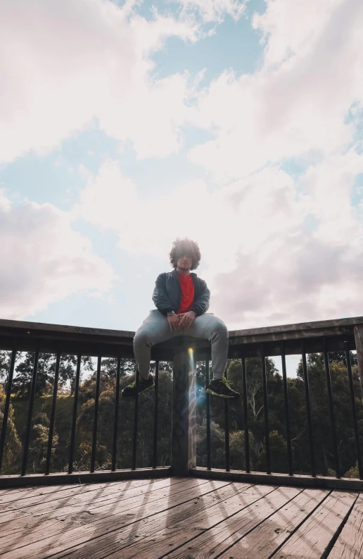 the person is sitting on a balcony railing overlooking a field