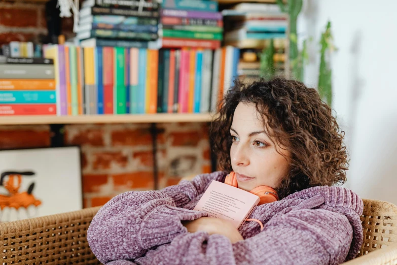 a woman sitting in a chair holding a pink book