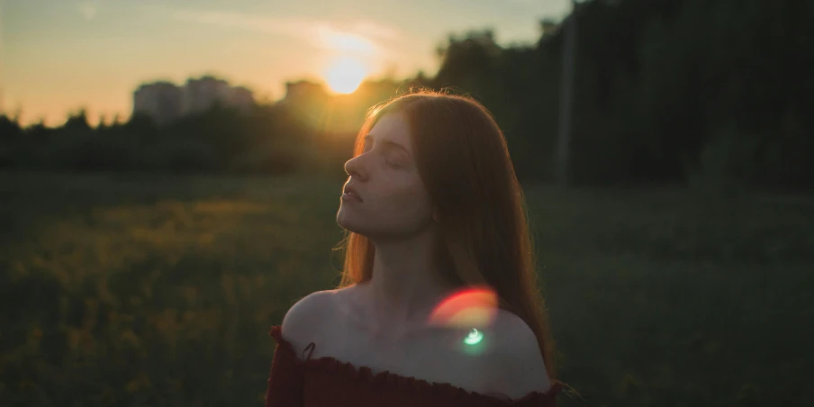 a woman in an off shoulder dress standing in a field