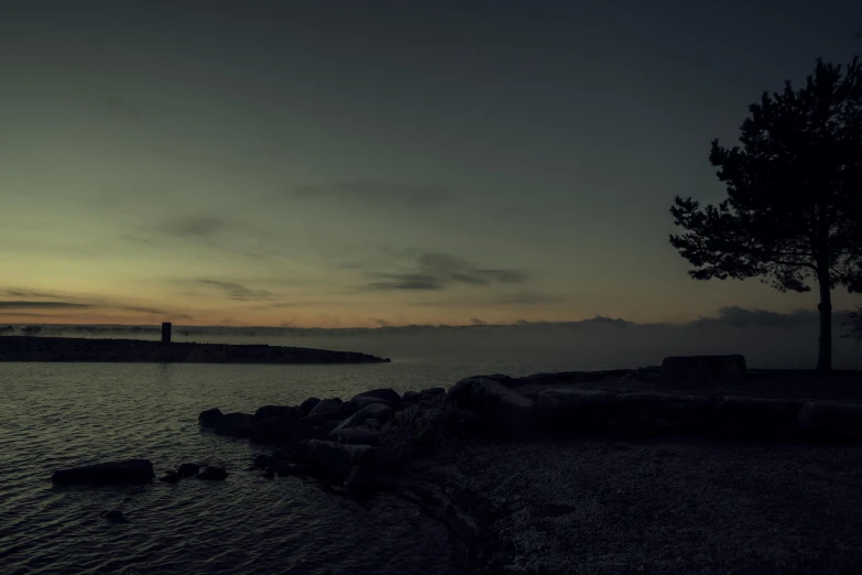 a lighthouse is silhouetted at sunset on the shore