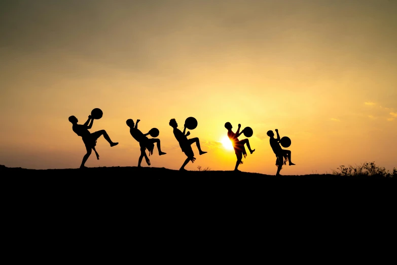 a group of people jumping in the air in front of a sunset