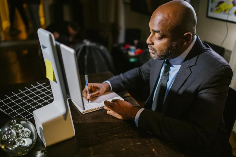 a black man in a suit writing on his computer