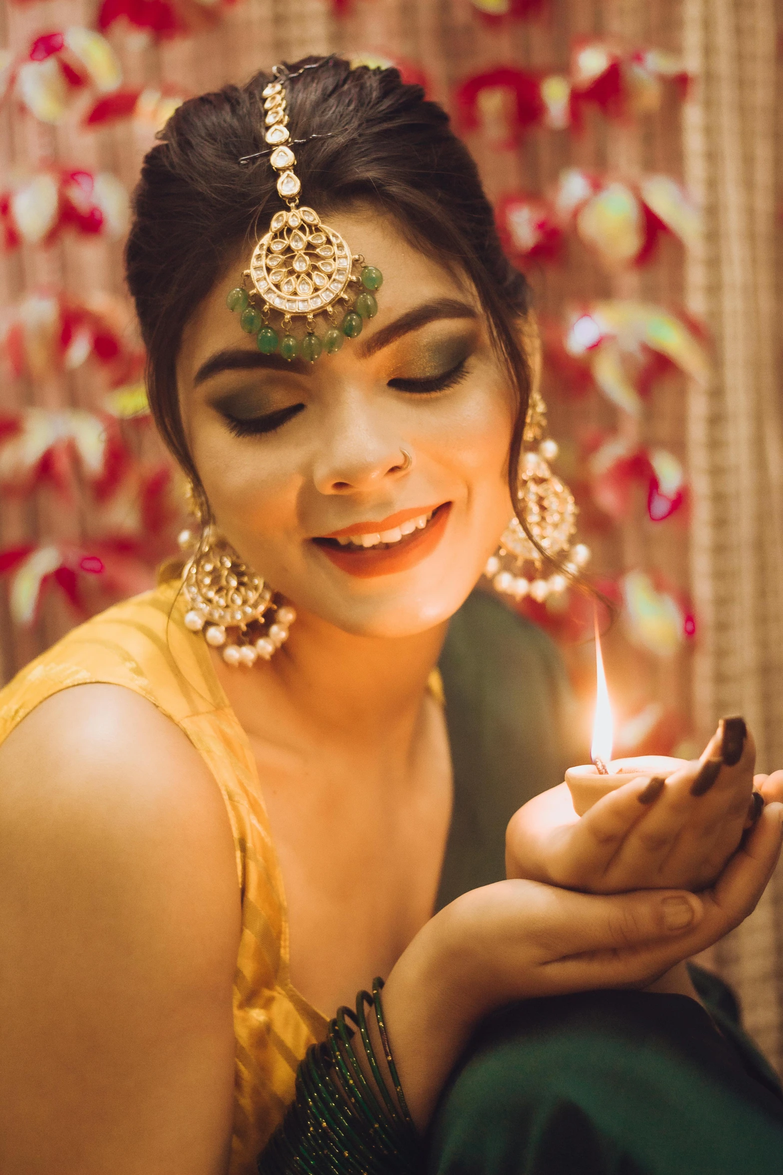 woman with indian jewelry smiling and looking at lit candle