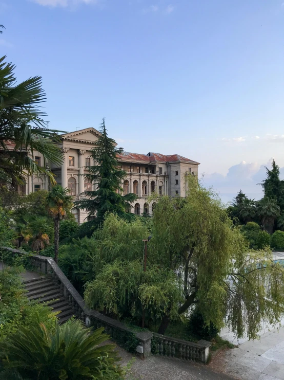 an old building with trees near water and stairs