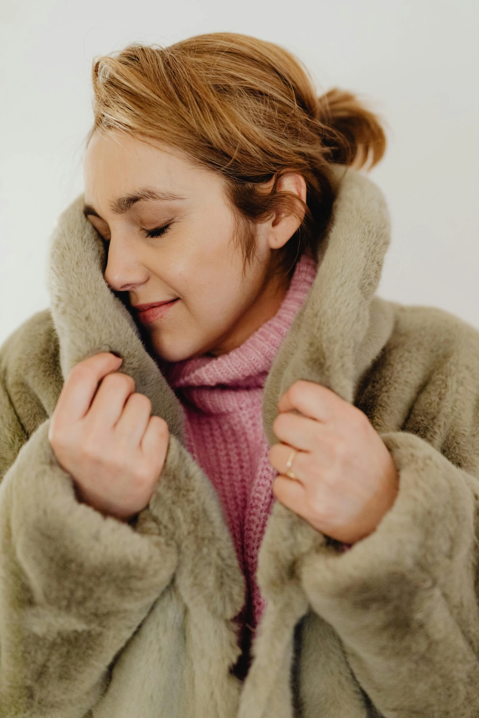 a young lady wearing a furry coat has a pink sweater on