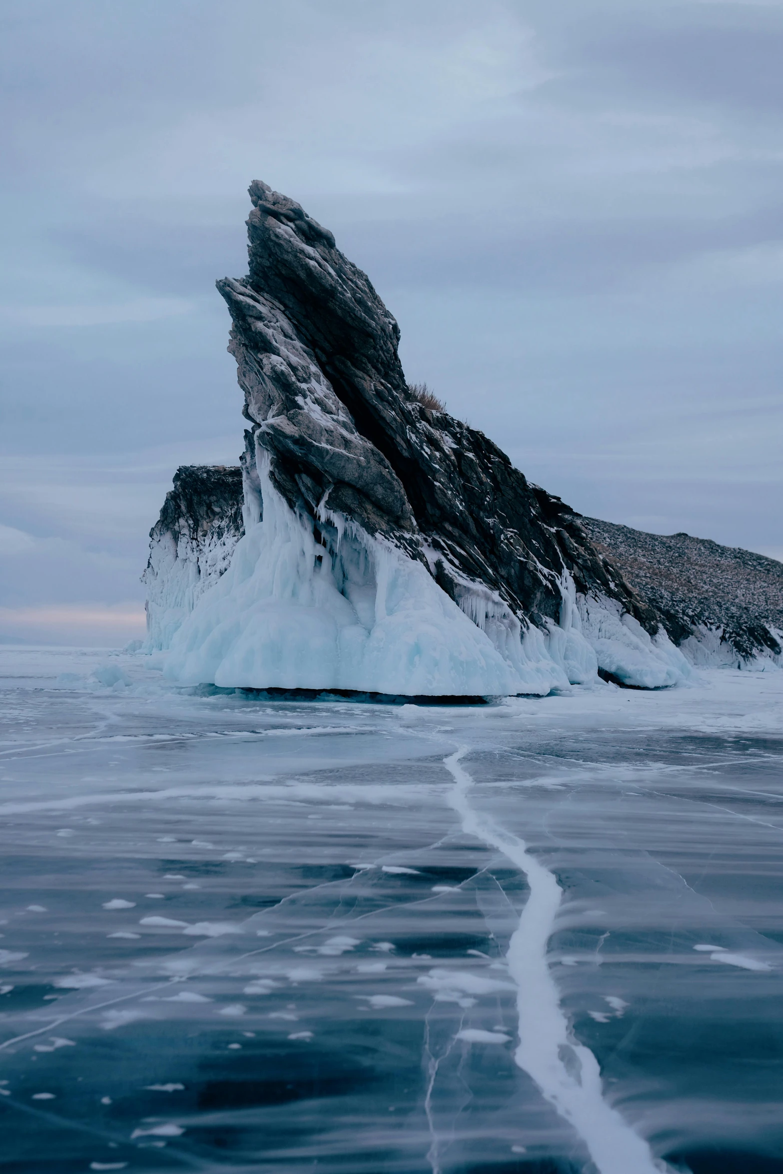 an iceberg with its snow covered base and ice in the foreground