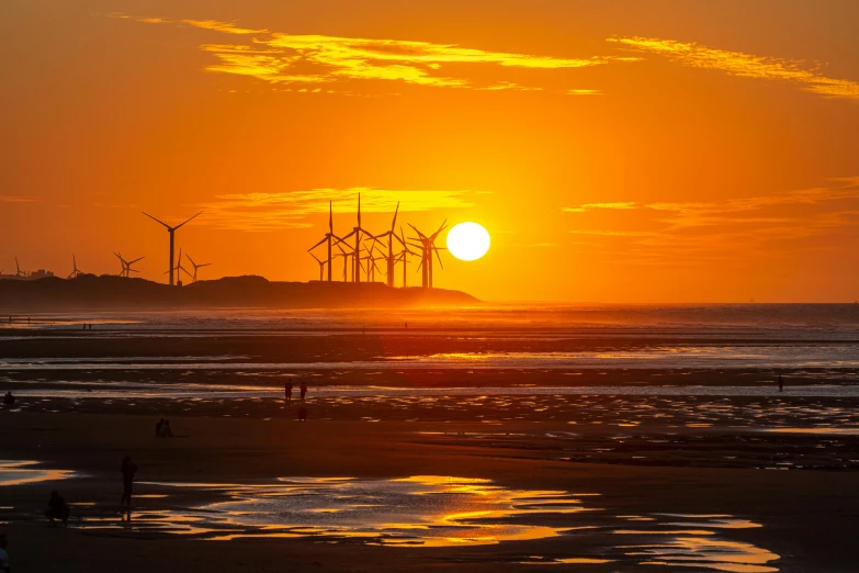 a sun that is setting in the sky with wind mills