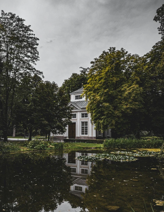 a house sits by a lake in the middle of a park