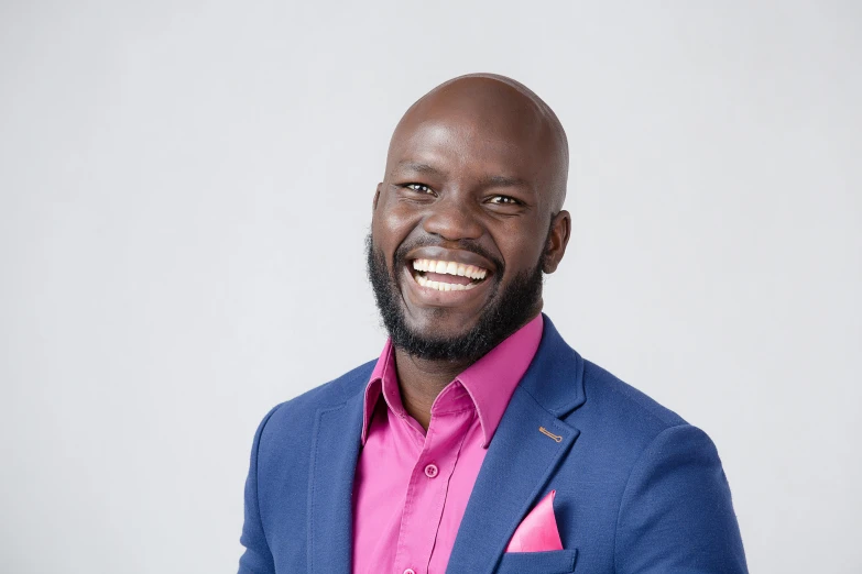 a man wearing a suit and pink shirt smiling