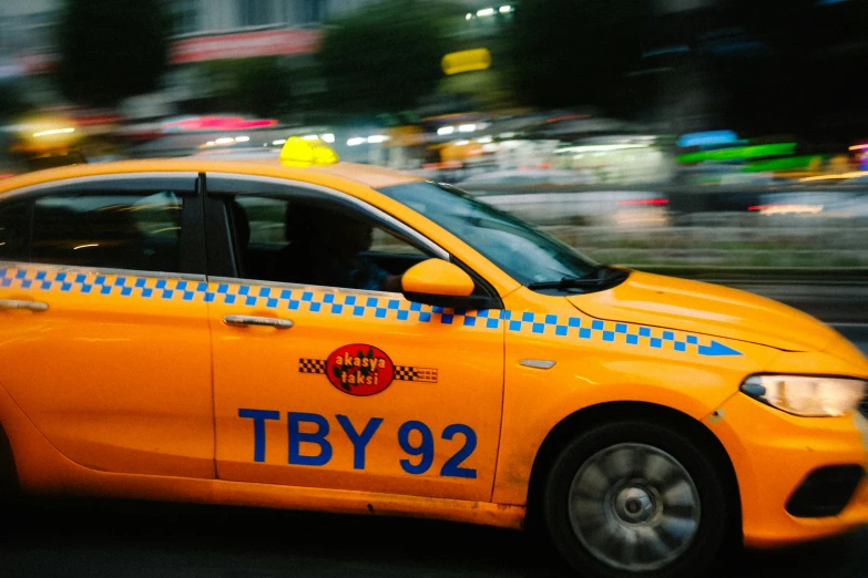 a yellow taxi cab driving on a busy city street