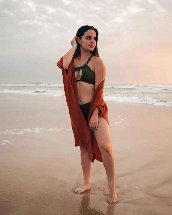 a woman in bikini wearing a cardigan posing on beach