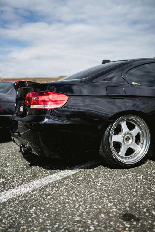 a black car in a parking lot on a partly cloudy day